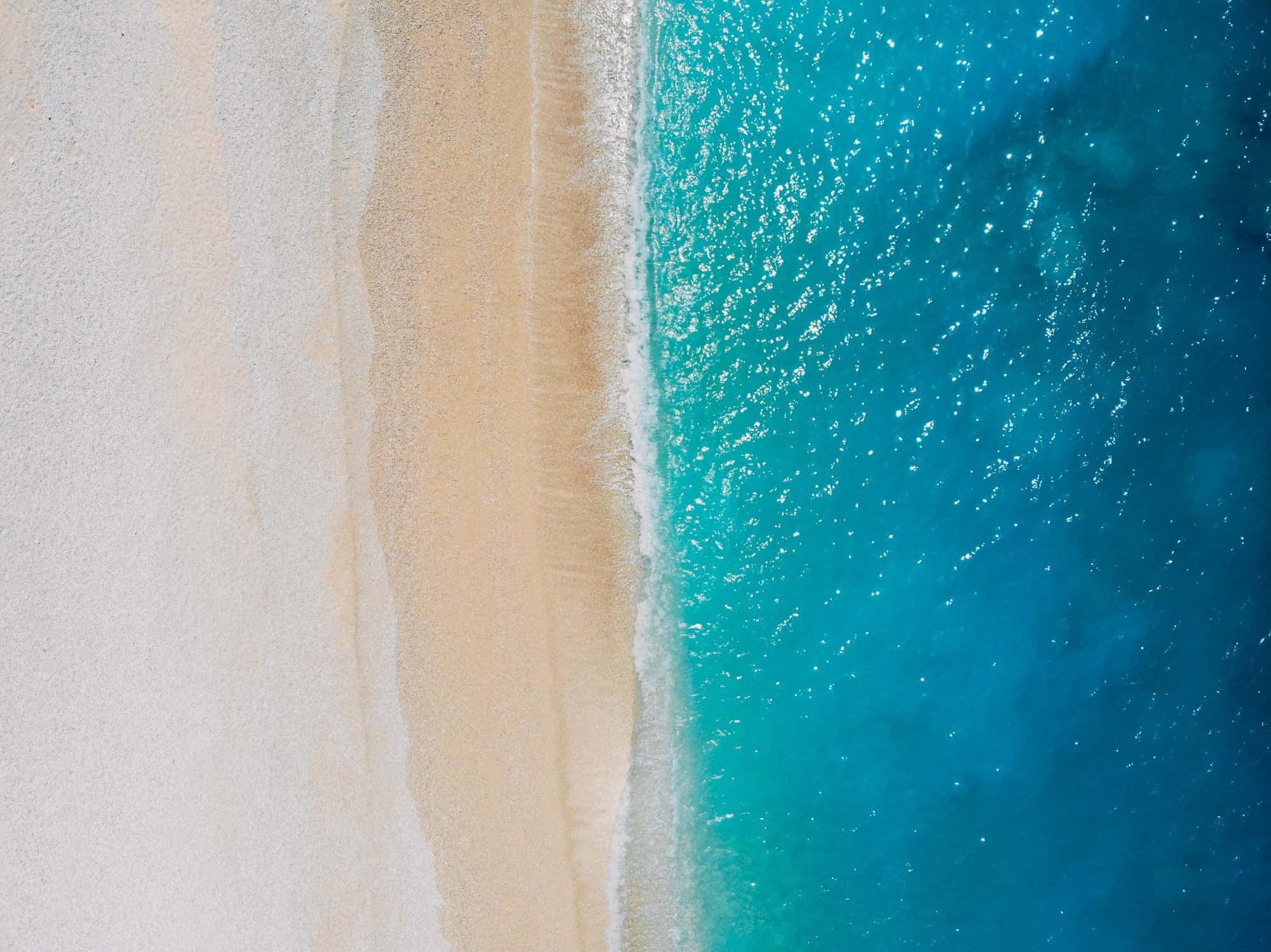 Turquoise waves washing a pale gold sand beach at Porto Katsiki, Lefkada, Greece